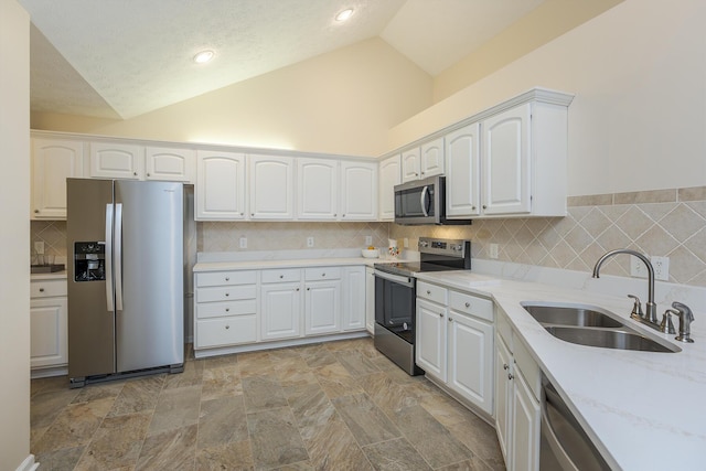 kitchen featuring light stone counters, stainless steel appliances, sink, high vaulted ceiling, and white cabinetry