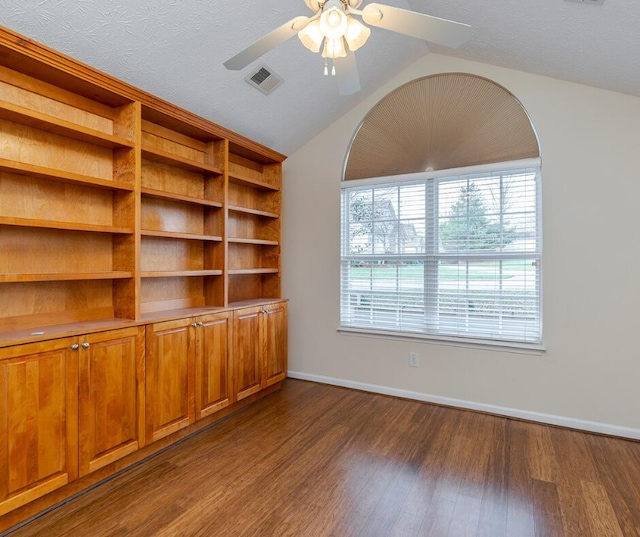 unfurnished living room featuring vaulted ceiling, ceiling fan, a textured ceiling, and dark hardwood / wood-style floors