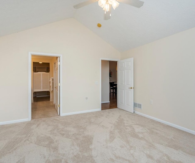 unfurnished bedroom with ceiling fan, high vaulted ceiling, a spacious closet, and light carpet