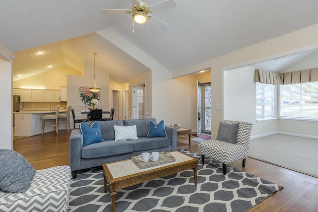 living room with a textured ceiling, ceiling fan, hardwood / wood-style floors, and lofted ceiling