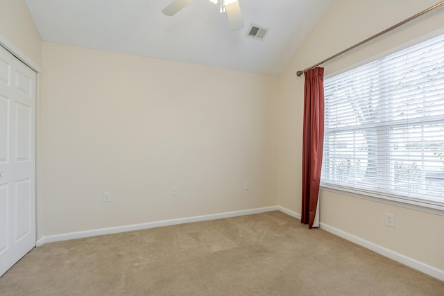 unfurnished room featuring light carpet, vaulted ceiling, a wealth of natural light, and ceiling fan