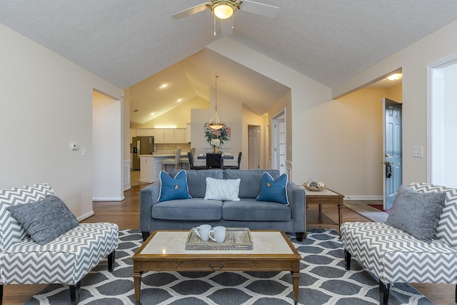 living room with hardwood / wood-style floors, ceiling fan, a textured ceiling, and vaulted ceiling