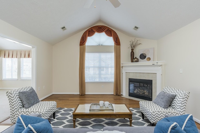 living room featuring a tiled fireplace, ceiling fan, hardwood / wood-style floors, and lofted ceiling