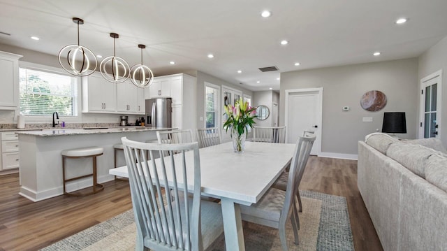 dining space with hardwood / wood-style floors, sink, and an inviting chandelier