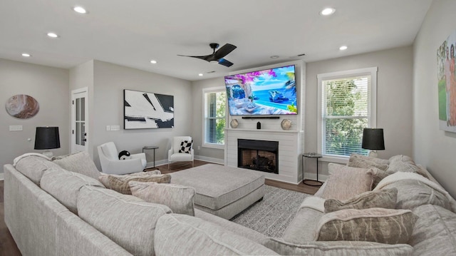 living room with wood-type flooring, a large fireplace, ceiling fan, and a healthy amount of sunlight