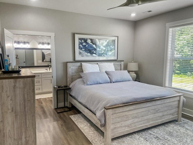 bedroom featuring connected bathroom, ceiling fan, and dark wood-type flooring