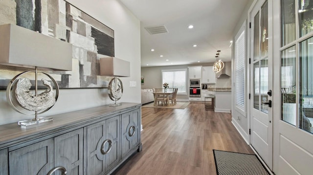 kitchen featuring hardwood / wood-style flooring, white cabinets, pendant lighting, and appliances with stainless steel finishes