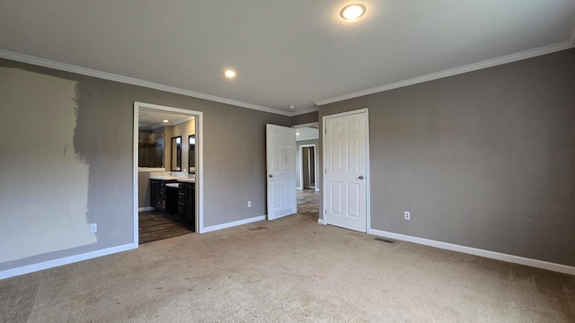 unfurnished bedroom with carpet, crown molding, and ensuite bath