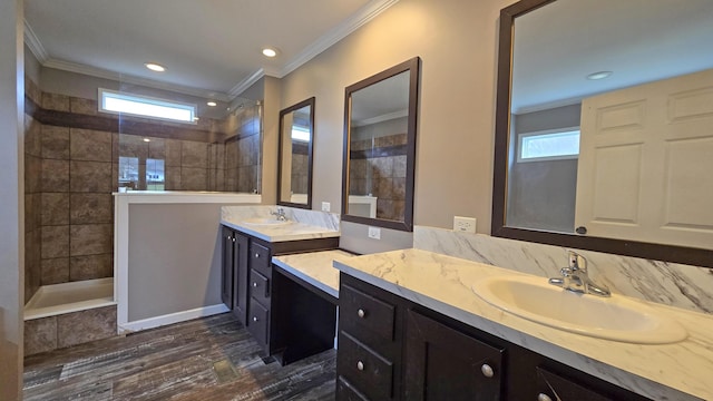 bathroom featuring hardwood / wood-style flooring, vanity, crown molding, and tiled shower