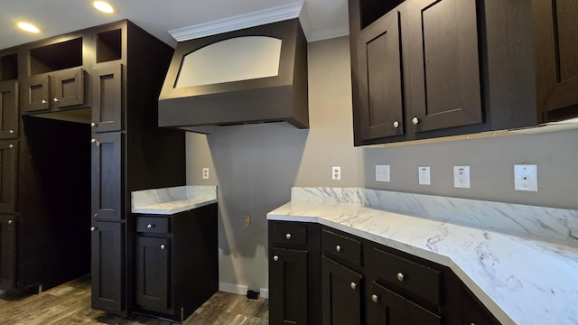 kitchen with dark brown cabinetry, ornamental molding, dark wood-type flooring, and exhaust hood