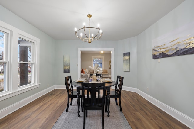 dining space with dark hardwood / wood-style floors and a notable chandelier