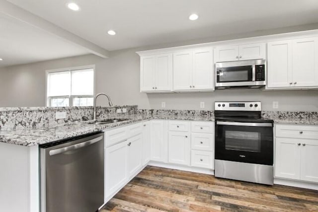 kitchen featuring dark wood-type flooring, sink, appliances with stainless steel finishes, white cabinetry, and kitchen peninsula