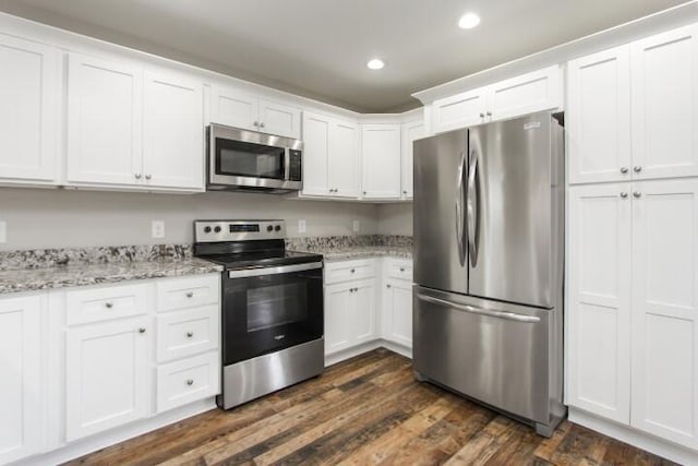 kitchen with white cabinetry, dark hardwood / wood-style flooring, light stone counters, and appliances with stainless steel finishes