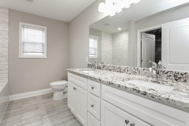 bathroom featuring toilet, a wealth of natural light, a shower, and vanity