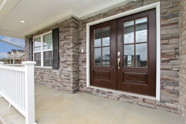 view of exterior entry with covered porch and french doors