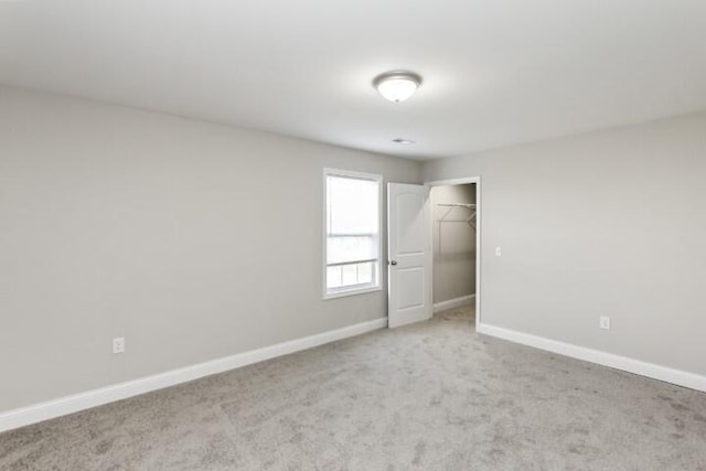 unfurnished bedroom with light colored carpet, a spacious closet, and a closet