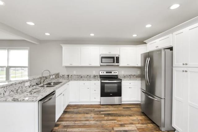 kitchen featuring sink, appliances with stainless steel finishes, white cabinetry, light stone counters, and kitchen peninsula