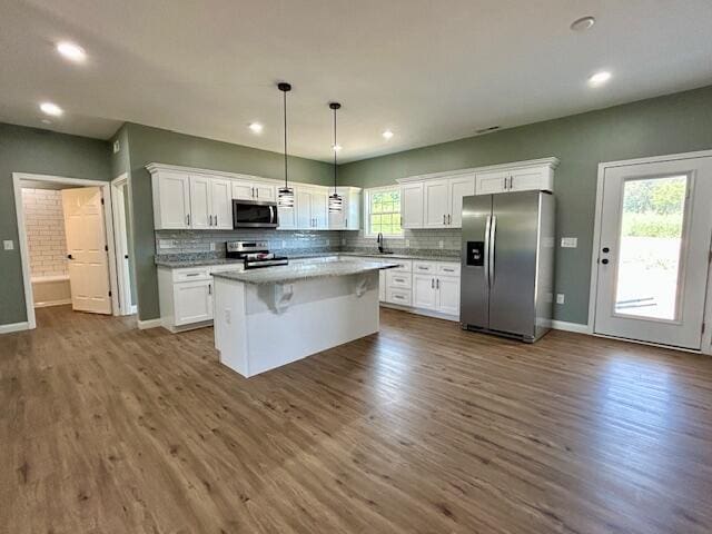 kitchen with decorative light fixtures, a kitchen island, white cabinetry, and stainless steel appliances