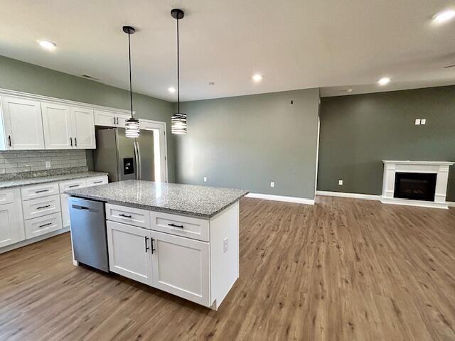 kitchen featuring white cabinetry, pendant lighting, light stone countertops, and appliances with stainless steel finishes