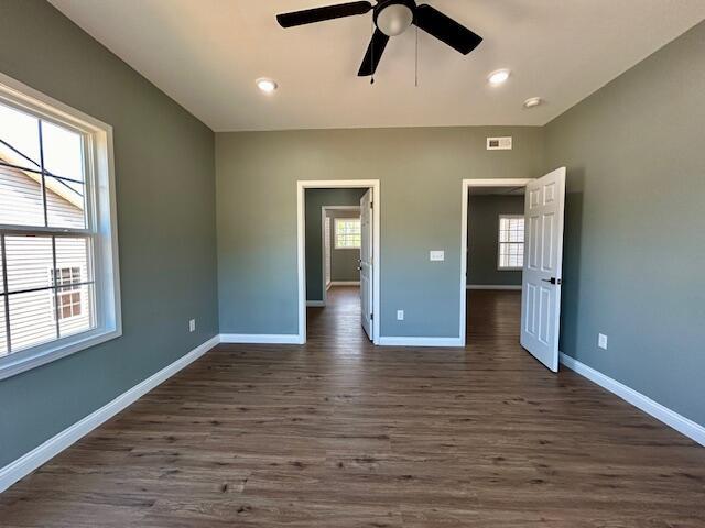 unfurnished bedroom with ceiling fan and dark wood-type flooring