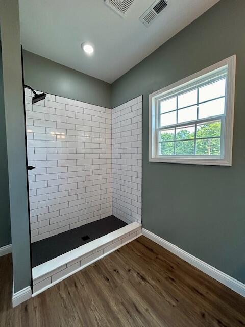 bathroom with wood-type flooring and tiled shower