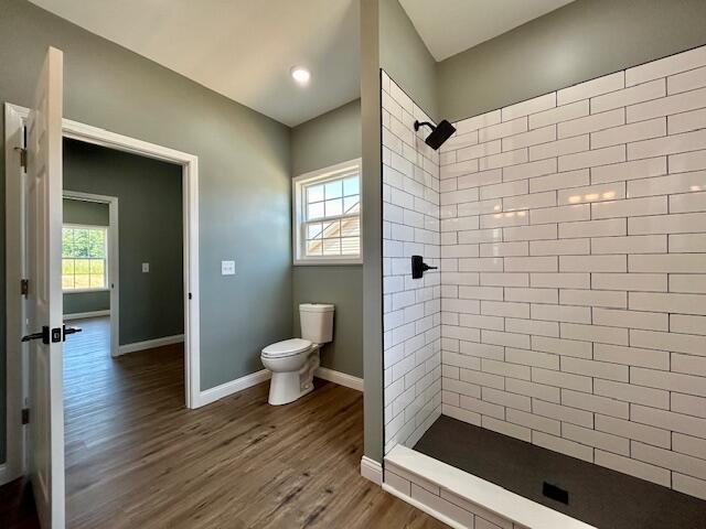 bathroom featuring tiled shower, wood-type flooring, toilet, and plenty of natural light