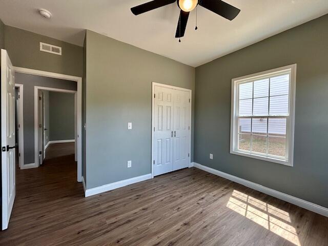 unfurnished bedroom featuring dark hardwood / wood-style flooring, a closet, and ceiling fan