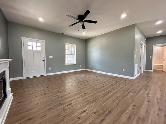 unfurnished living room featuring ceiling fan and dark wood-type flooring