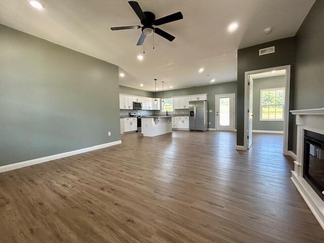 unfurnished living room featuring ceiling fan and dark hardwood / wood-style flooring