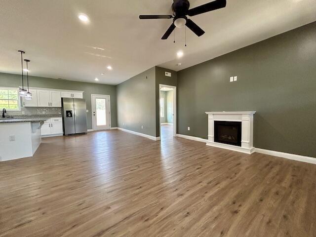 unfurnished living room with ceiling fan and hardwood / wood-style flooring