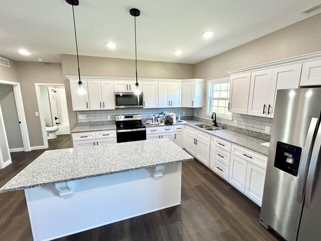 kitchen with stainless steel appliances, white cabinetry, and hanging light fixtures