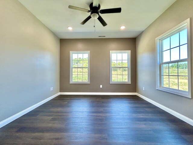 empty room with dark hardwood / wood-style floors, ceiling fan, and a healthy amount of sunlight