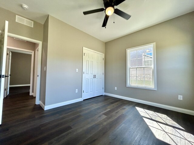 unfurnished bedroom with dark hardwood / wood-style flooring, a closet, and ceiling fan