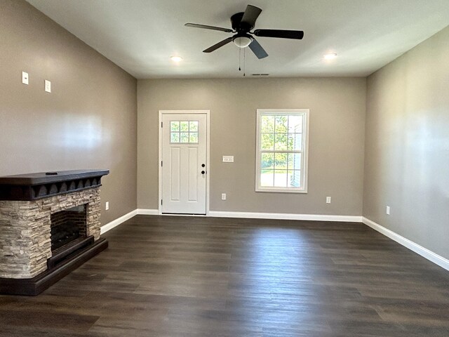 entryway featuring dark hardwood / wood-style flooring, a stone fireplace, and ceiling fan