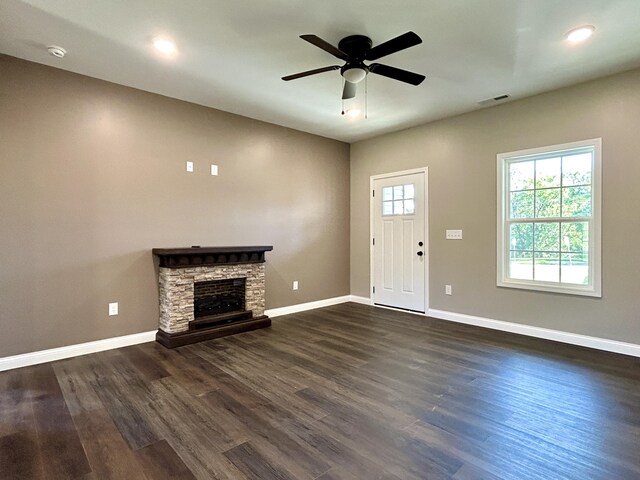 unfurnished living room featuring ceiling fan, a fireplace, and dark wood-type flooring