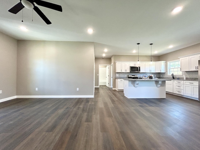 kitchen featuring appliances with stainless steel finishes, a kitchen breakfast bar, decorative light fixtures, white cabinets, and a center island