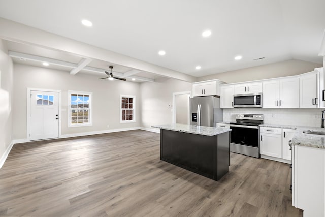 kitchen featuring decorative backsplash, appliances with stainless steel finishes, open floor plan, a sink, and a kitchen island