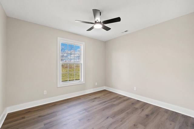 empty room with visible vents, ceiling fan, baseboards, and wood finished floors