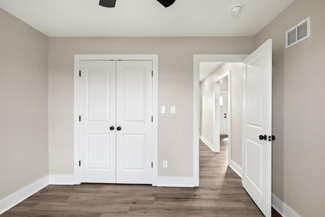 unfurnished bedroom featuring hardwood / wood-style flooring, ceiling fan, and a closet