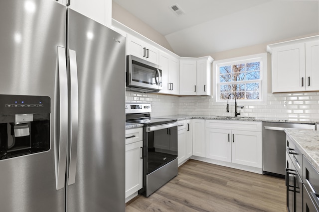 kitchen with light stone countertops, appliances with stainless steel finishes, sink, and white cabinets