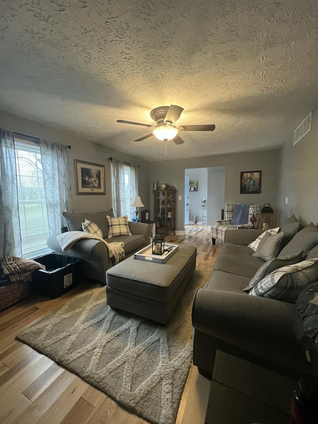 living room featuring hardwood / wood-style floors, a textured ceiling, and ceiling fan