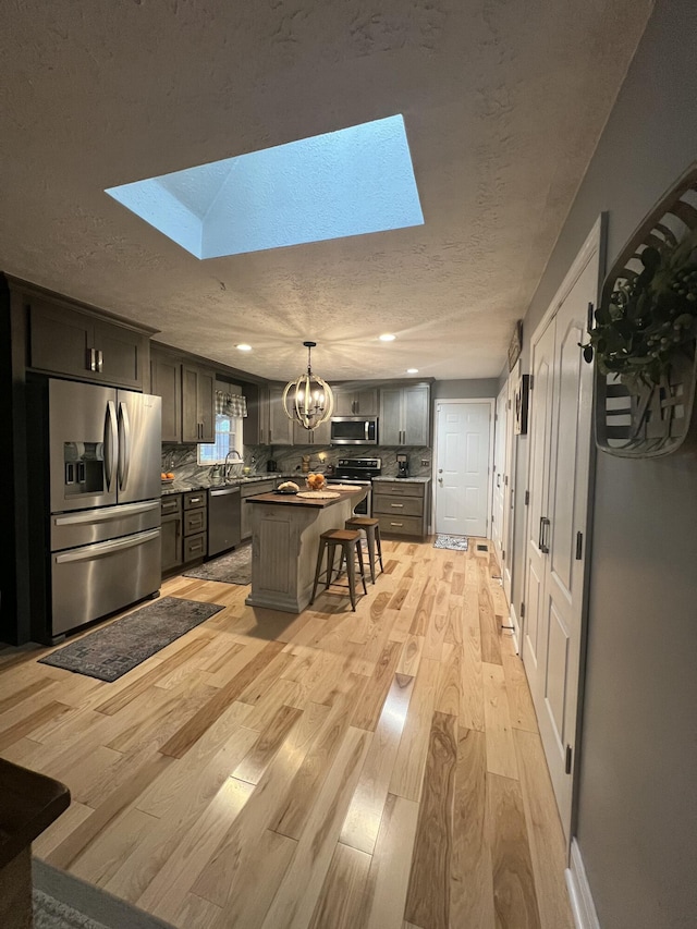 kitchen with tasteful backsplash, a skylight, a kitchen island, and appliances with stainless steel finishes