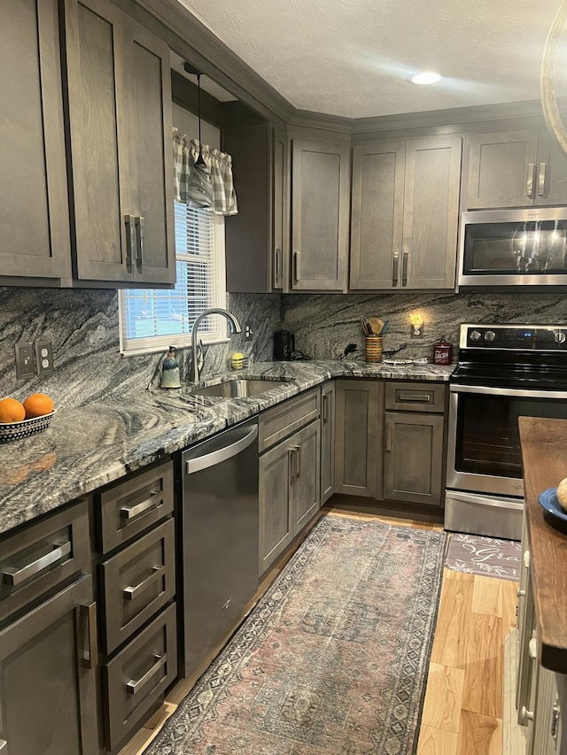 kitchen featuring dark stone counters, hanging light fixtures, sink, dark brown cabinets, and stainless steel appliances