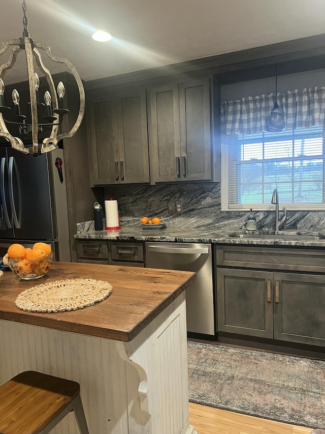 kitchen featuring dishwasher, sink, decorative light fixtures, and wooden counters