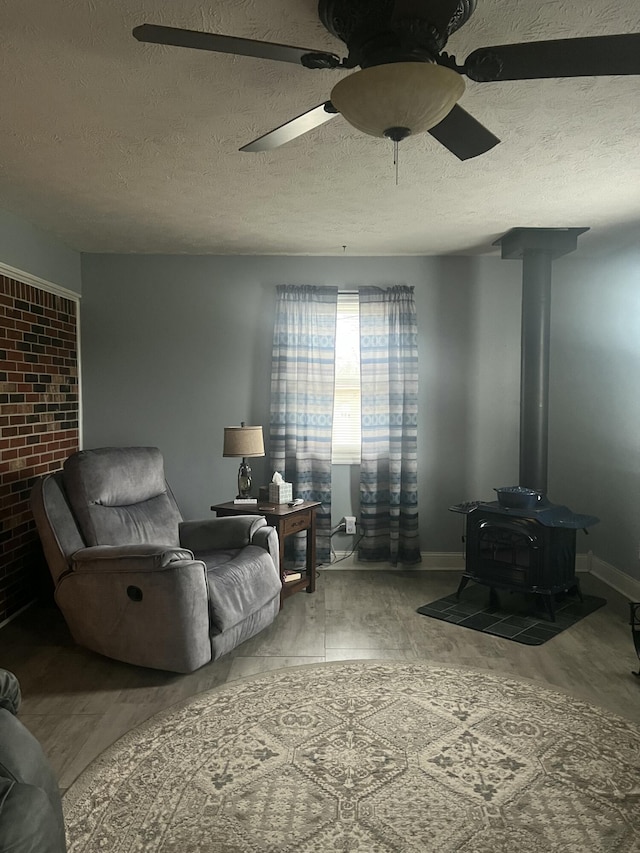 living room with ceiling fan, a wood stove, and a textured ceiling