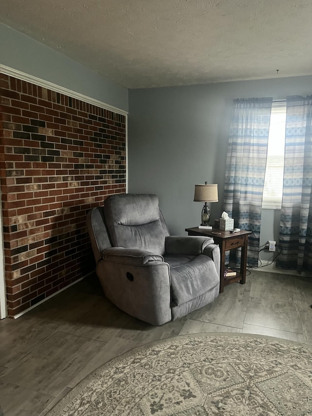 sitting room with brick wall and a textured ceiling