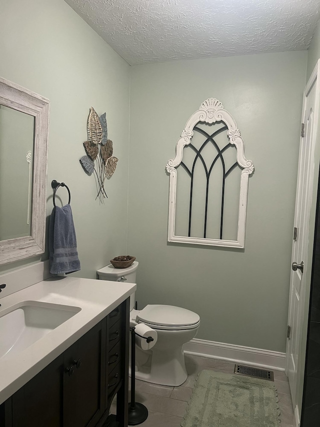 bathroom featuring tile patterned flooring, vanity, a textured ceiling, and toilet