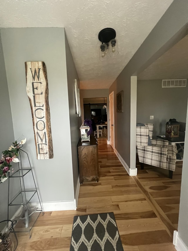 hallway featuring a textured ceiling and light hardwood / wood-style flooring