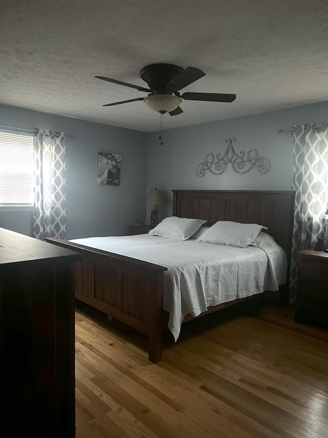 bedroom with wood-type flooring, a textured ceiling, and ceiling fan