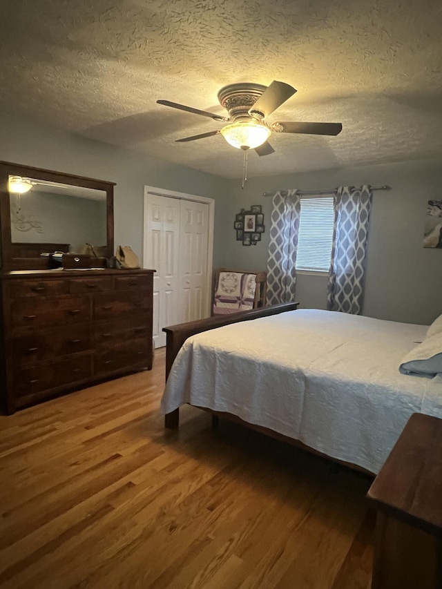 bedroom featuring hardwood / wood-style flooring, ceiling fan, a textured ceiling, and a closet